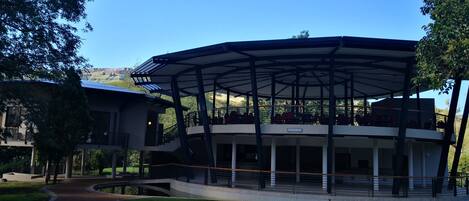 A modern building with a covered outdoor area, a curved pathway, and a view of a mountainous landscape.