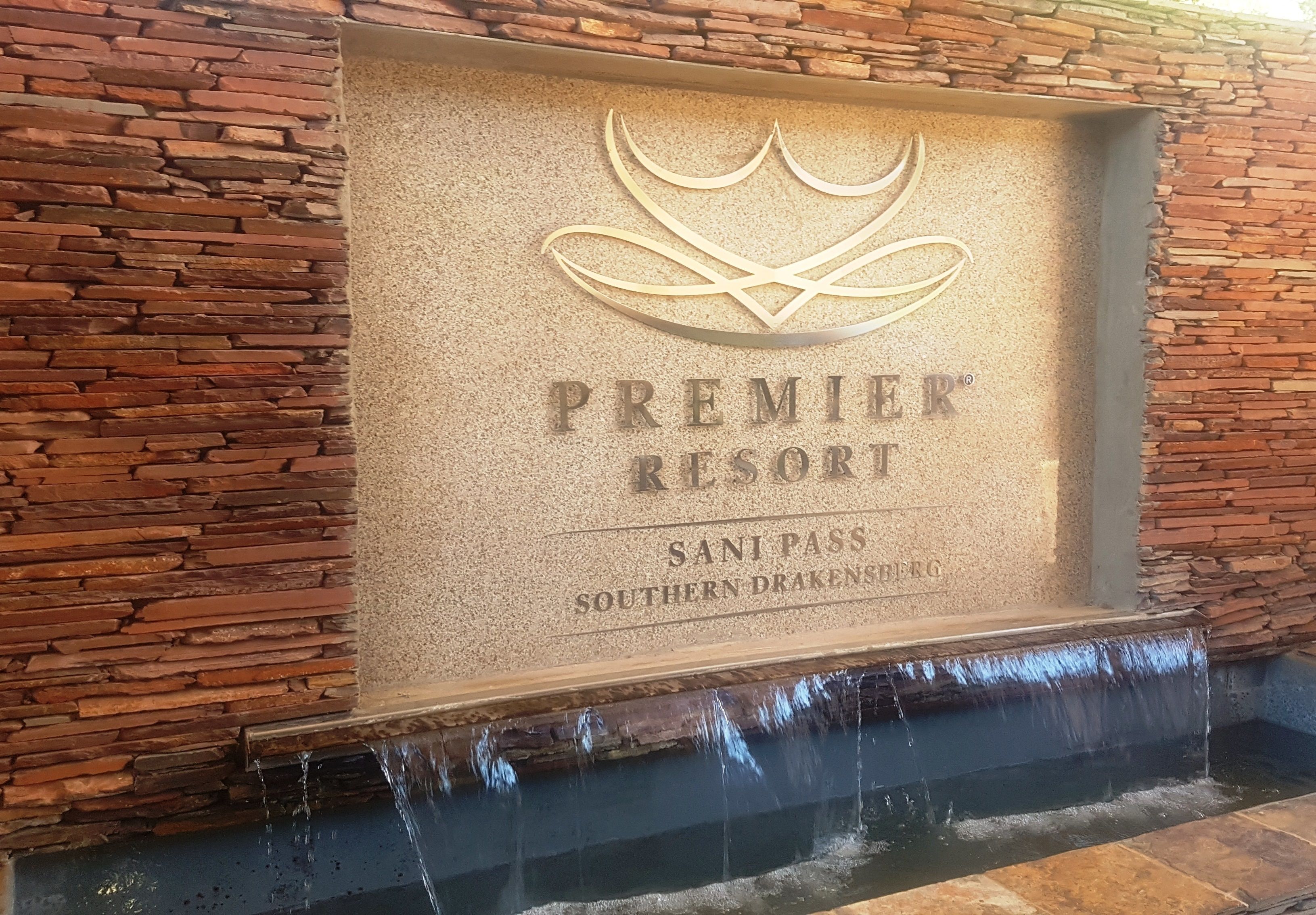 Um muro de pedra com uma placa que diz 'Premier Resort Sani Pass Southern Drakensberg'.