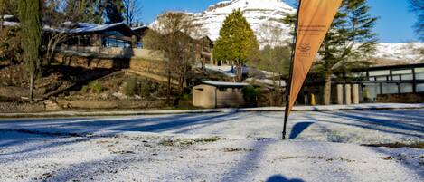 A snowy landscape with a flag, a building, and a mountain in the background.