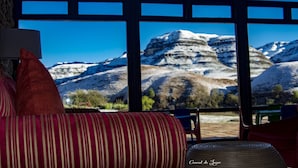 A room with a large window offering a view of snow-covered mountains. - Premier Resort Sani Pass (Himeville)