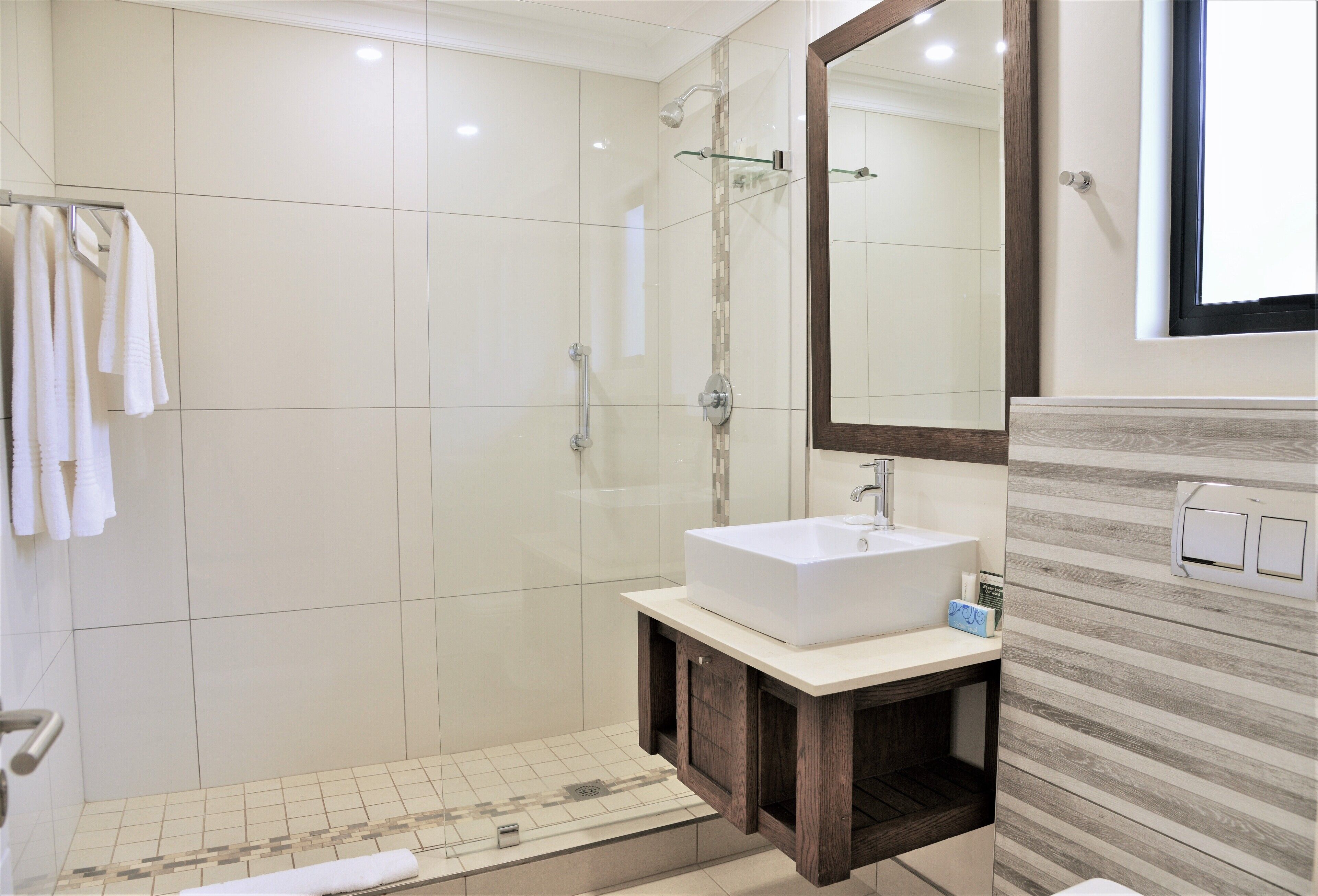 A modern bathroom with a large mirror, a white sink, and a shower area.
