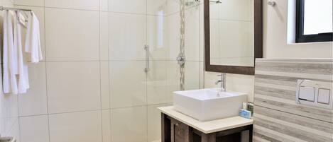 Un baño moderno con un espejo grande, un lavabo blanco y una zona de ducha.