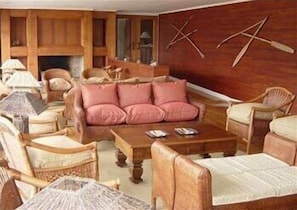 A cozy living room with a sofa, wooden chairs, a coffee table, and a fireplace.