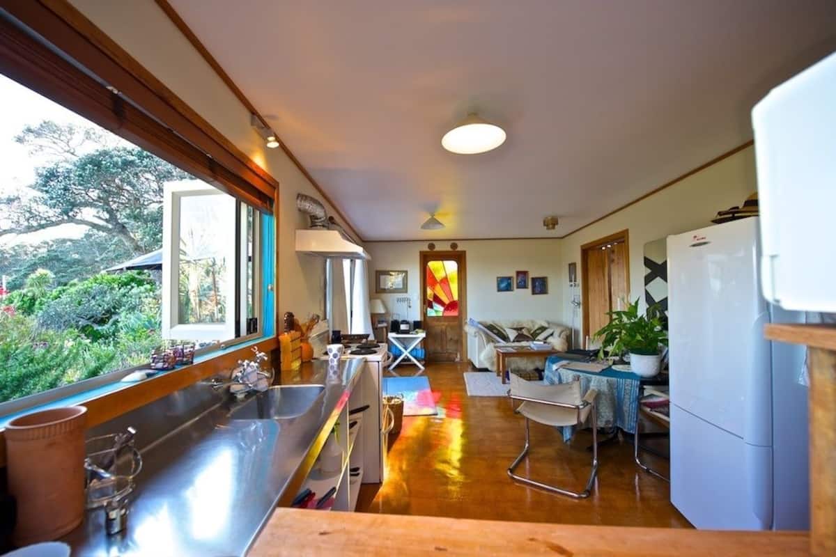 A modern kitchen with a large window, a dining area, and a living space.