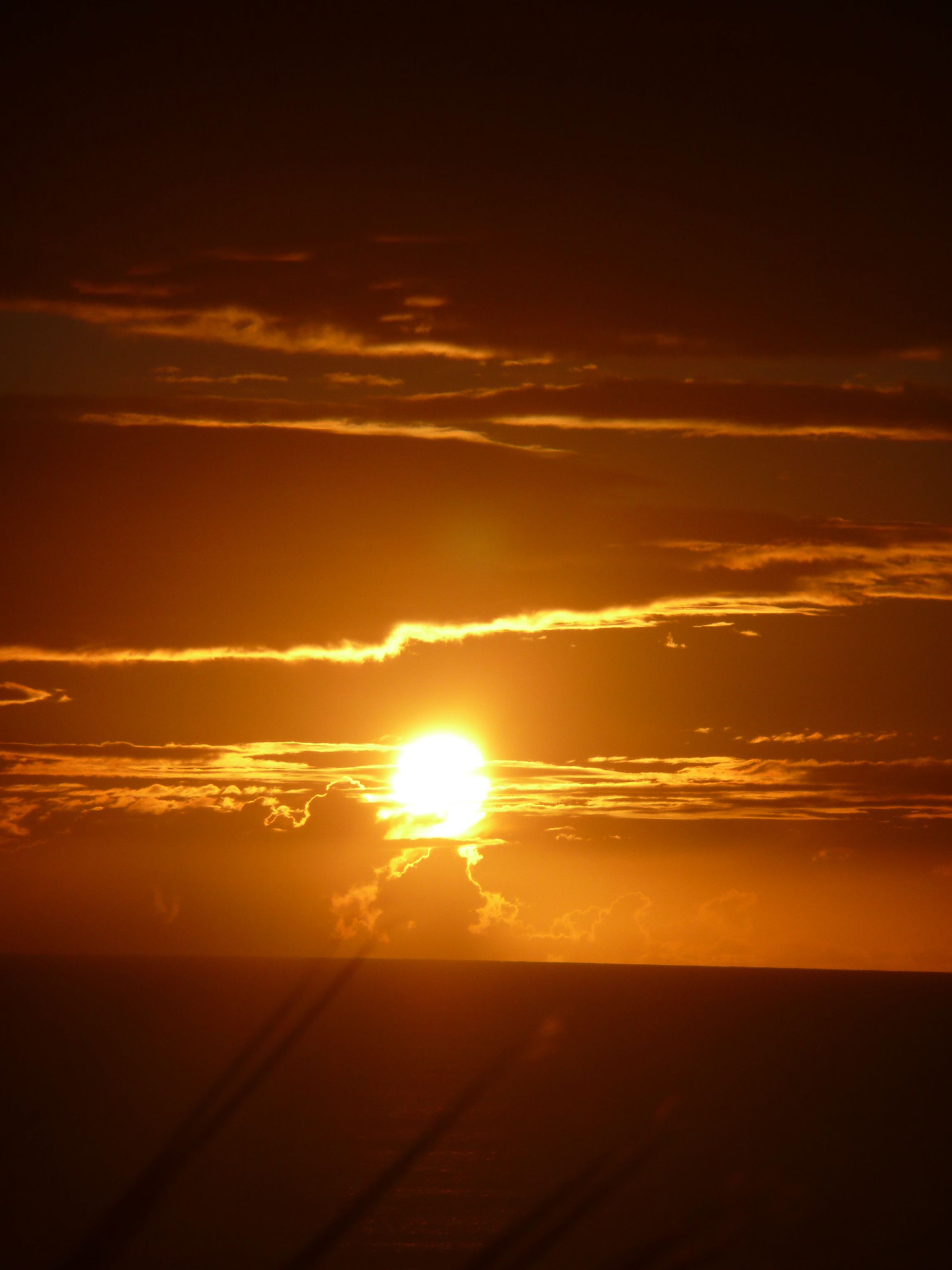A sunset with the sun partially obscured by clouds.