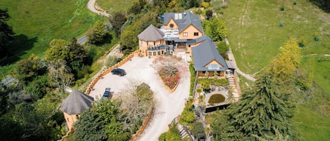 A large, multi-story house with a spacious driveway and a well-maintained garden.