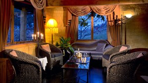A cozy room with wicker furniture, a glass coffee table, and a view of trees outside. - The Mudcastle (Upper Moutere)