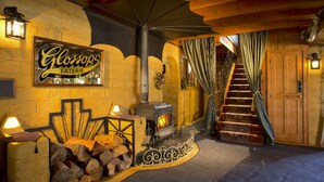 A cozy interior with a wood-burning stove, a staircase, and a sign for 'Glomops EATERIE'. - The Mudcastle (Upper Moutere)