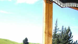 A wooden structure with a small building and a garden with pink flowers. - The Mudcastle (Upper Moutere)