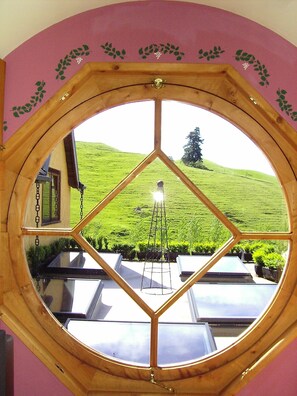 Enjoy a panoramic view of the lush hillside from this room's unique window, featuring a metal ladder for easy access to the upper level.