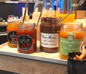 A selection of jars with labels, a spoon, and a black mug on a counter. - Hotel Sixteen Paris Montrouge (Montrouge)