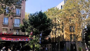 A café with outdoor seating, a bicycle parked nearby, and a tree in the foreground. - Hotel Sixteen Paris Montrouge (Montrouge)