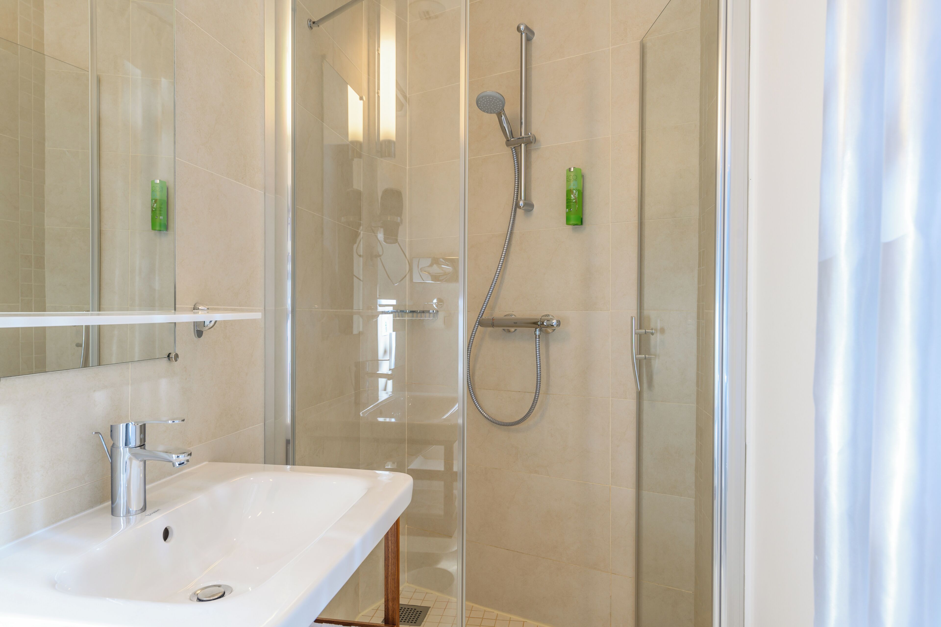 Un baño moderno con ducha de vidrio, lavamanos blanco y espejo.