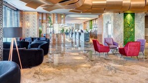 A spacious lobby with a polished marble floor, modern seating areas, and a decorative wall with a vertical garden. - Emerald Hotel Pristina, Kosovo (Preoce)