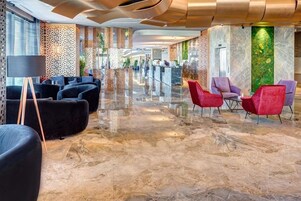 Un vestíbulo amplio con piso de mármol pulido, zonas de estar modernas y una pared decorativa con jardín vertical.