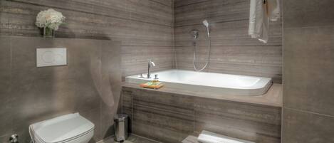 Une salle de bain moderne équipée de toilettes, d’un bidet et d’une baignoire.
