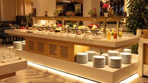 A buffet setup with various food items and beverages, surrounded by stacks of plates and glasses. - Emerald Hotel Pristina, Kosovo (Preoce)