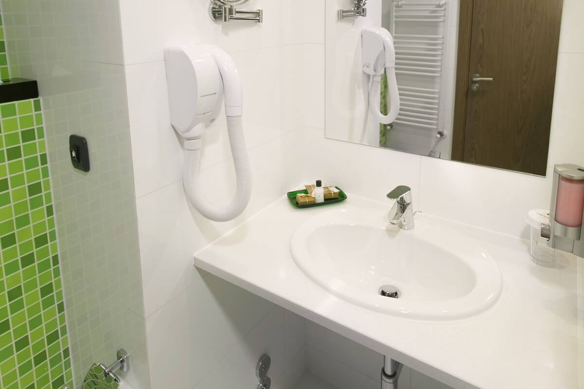 A bathroom with a white sink, a mirror, a hairdryer, and a towel rack.