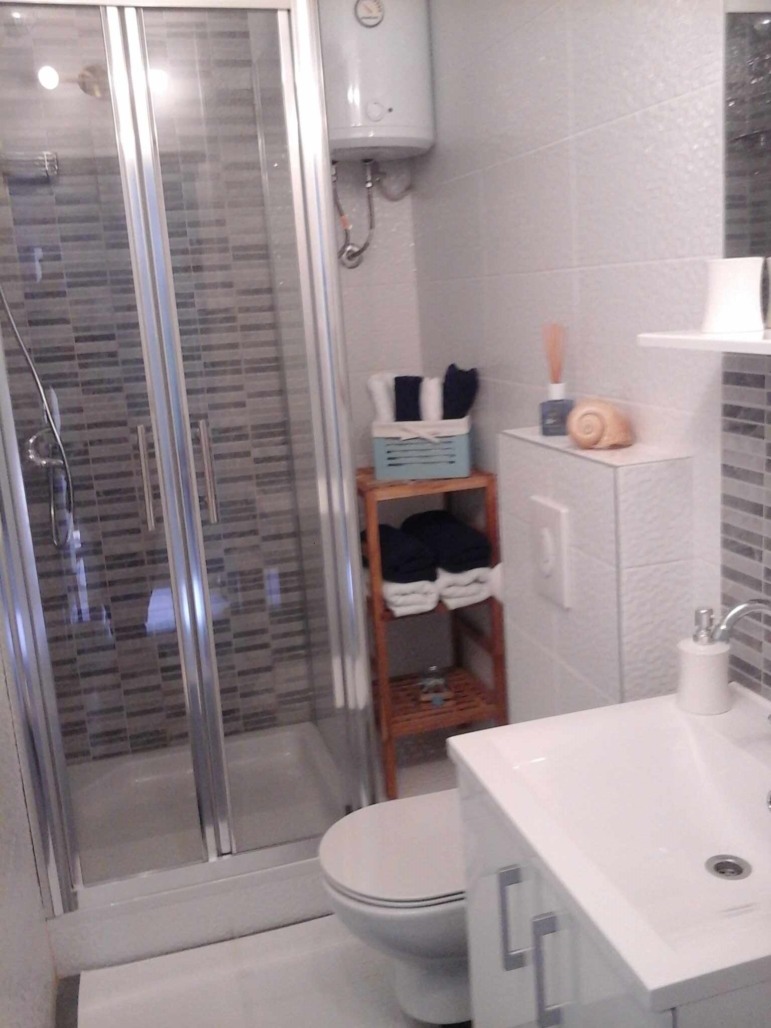 Une salle de bain moderne avec une douche à parois de verre, des toilettes et un lavabo avec un miroir.