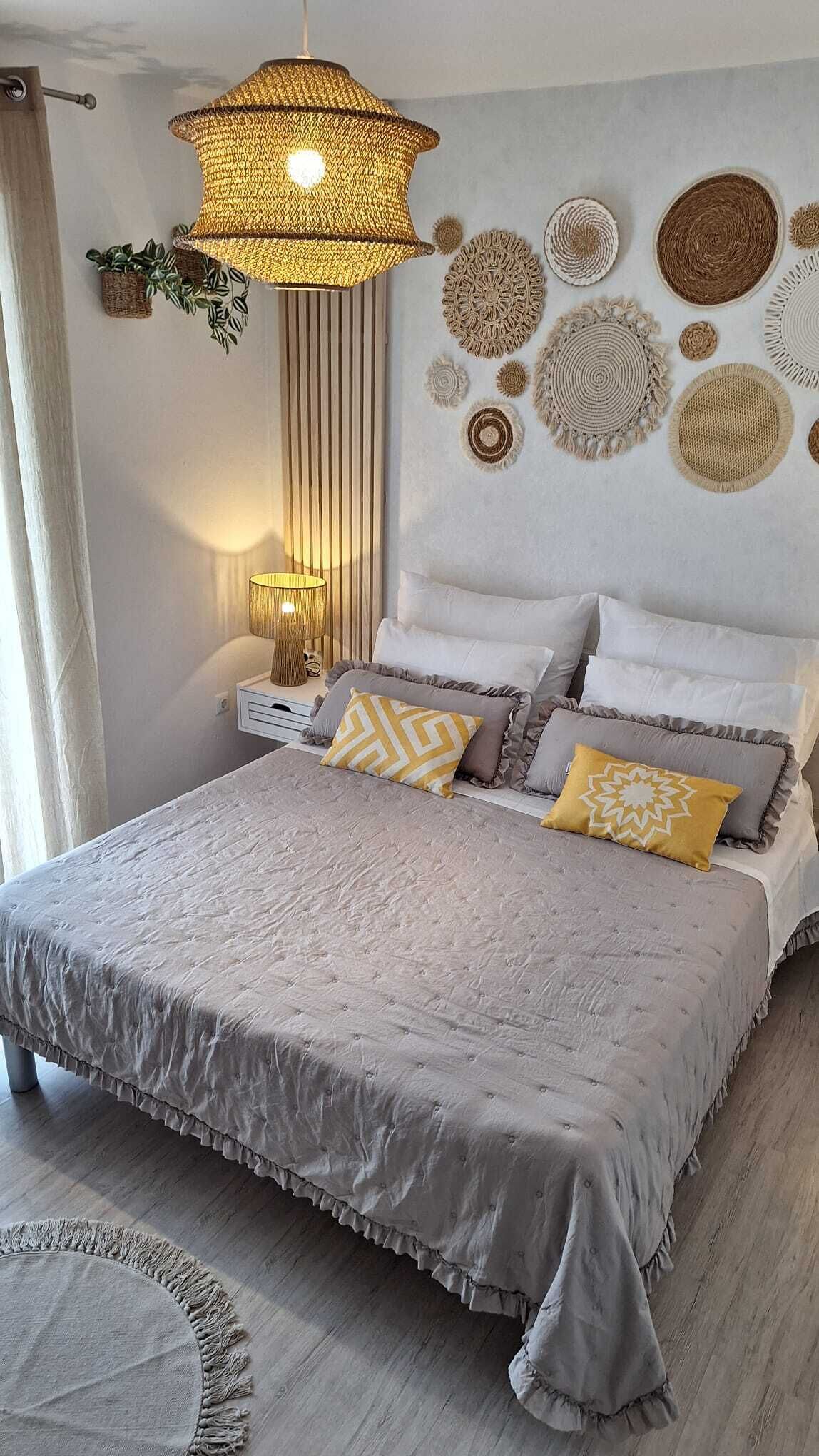 Un dormitorio con cama, lámparas de noche y decoración en la pared.