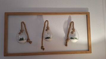 A wooden-framed wall display with three hanging glass terrariums containing small plants.