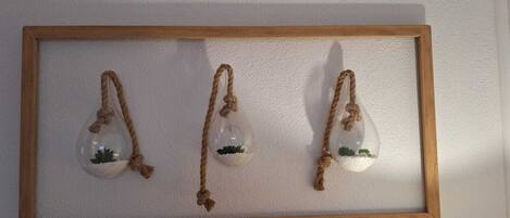 A wooden-framed wall display with three hanging glass terrariums containing small plants.