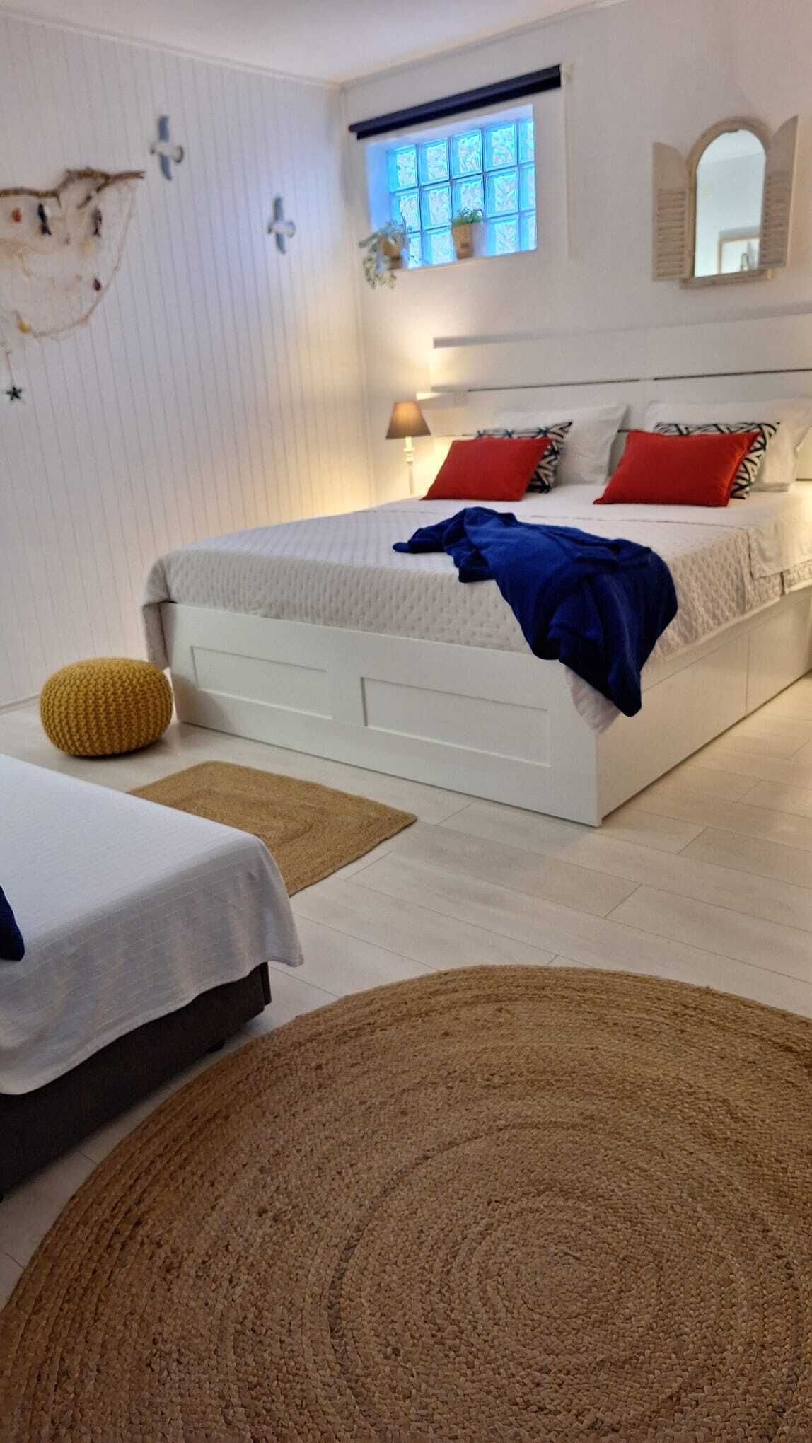 Un dormitorio con cama, mesitas de noche, ventana y espejo.