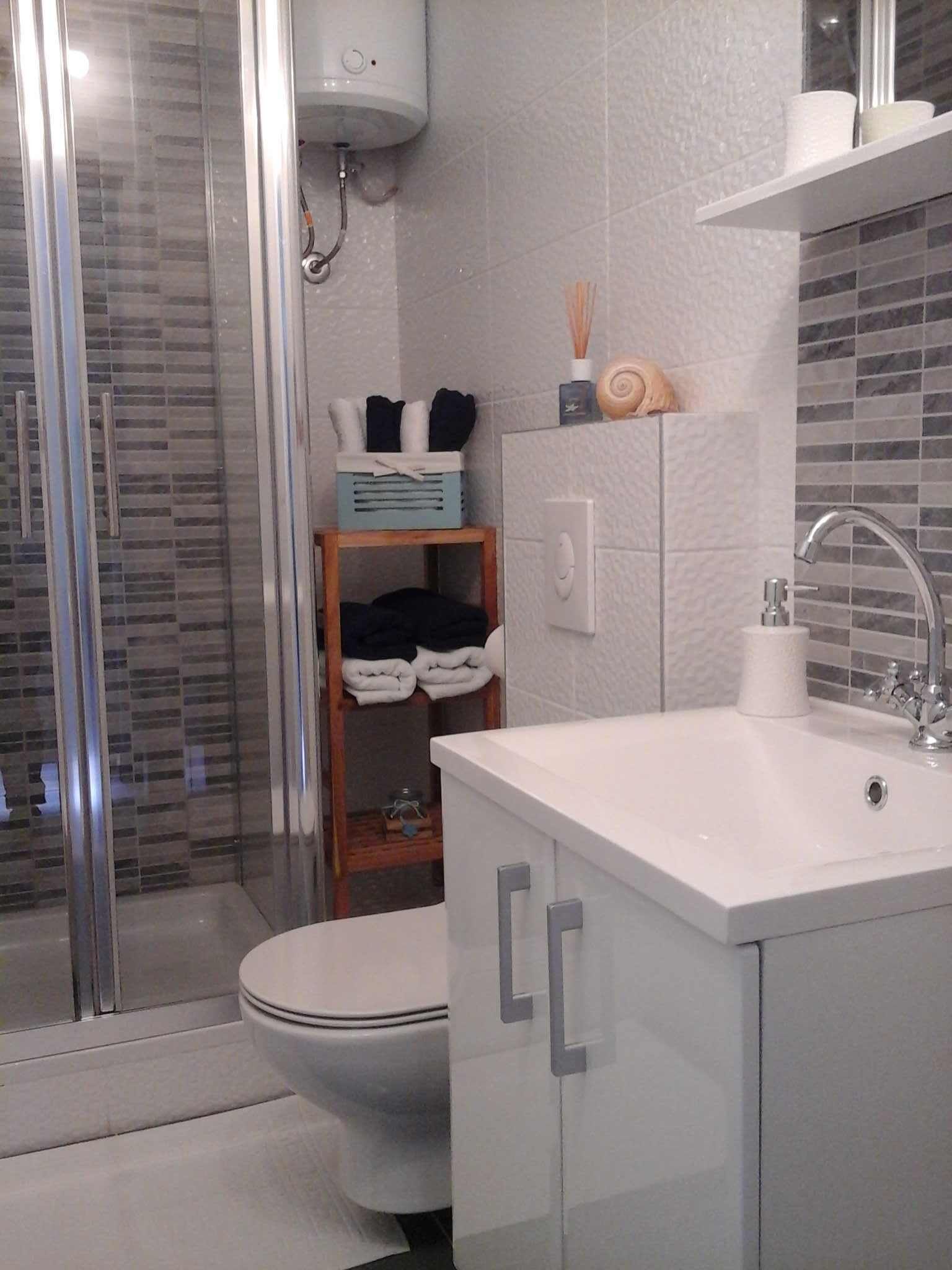 Un baño moderno con cabina de ducha de vidrio, inodoro, lavabo con espejo y toallero.