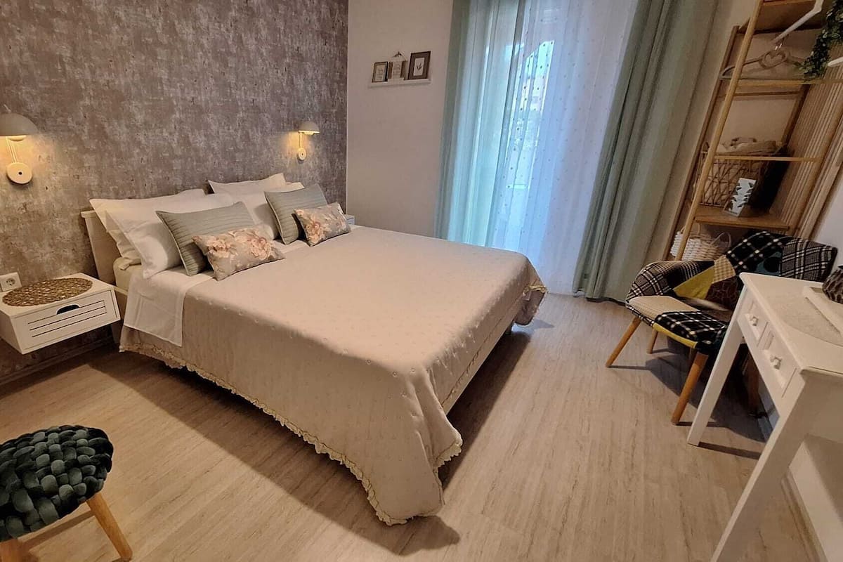 Ein Schlafzimmer mit einem großen Bett, Nachttischen, einem Sessel und einem Tisch mit Blumen.