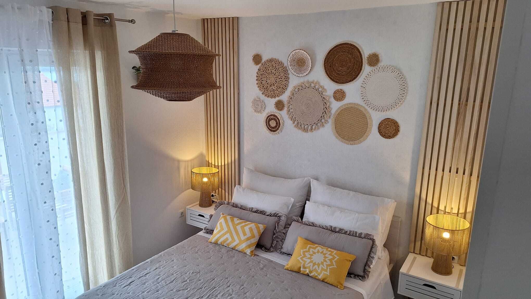 A bedroom with a bed, two bedside tables, a hanging light fixture, and wall decor.