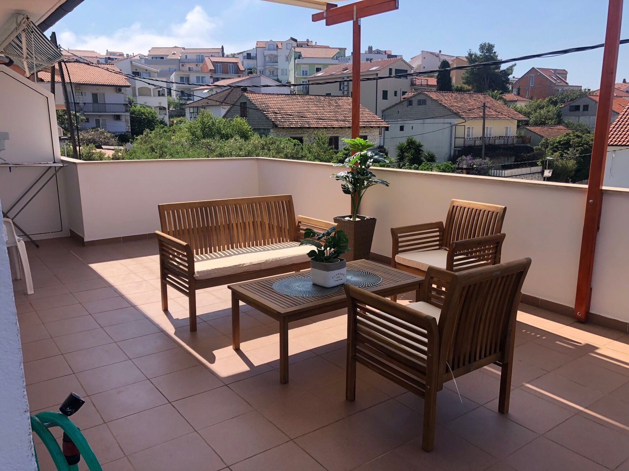 A balcony with a wooden table, two chairs, and a potted plant.