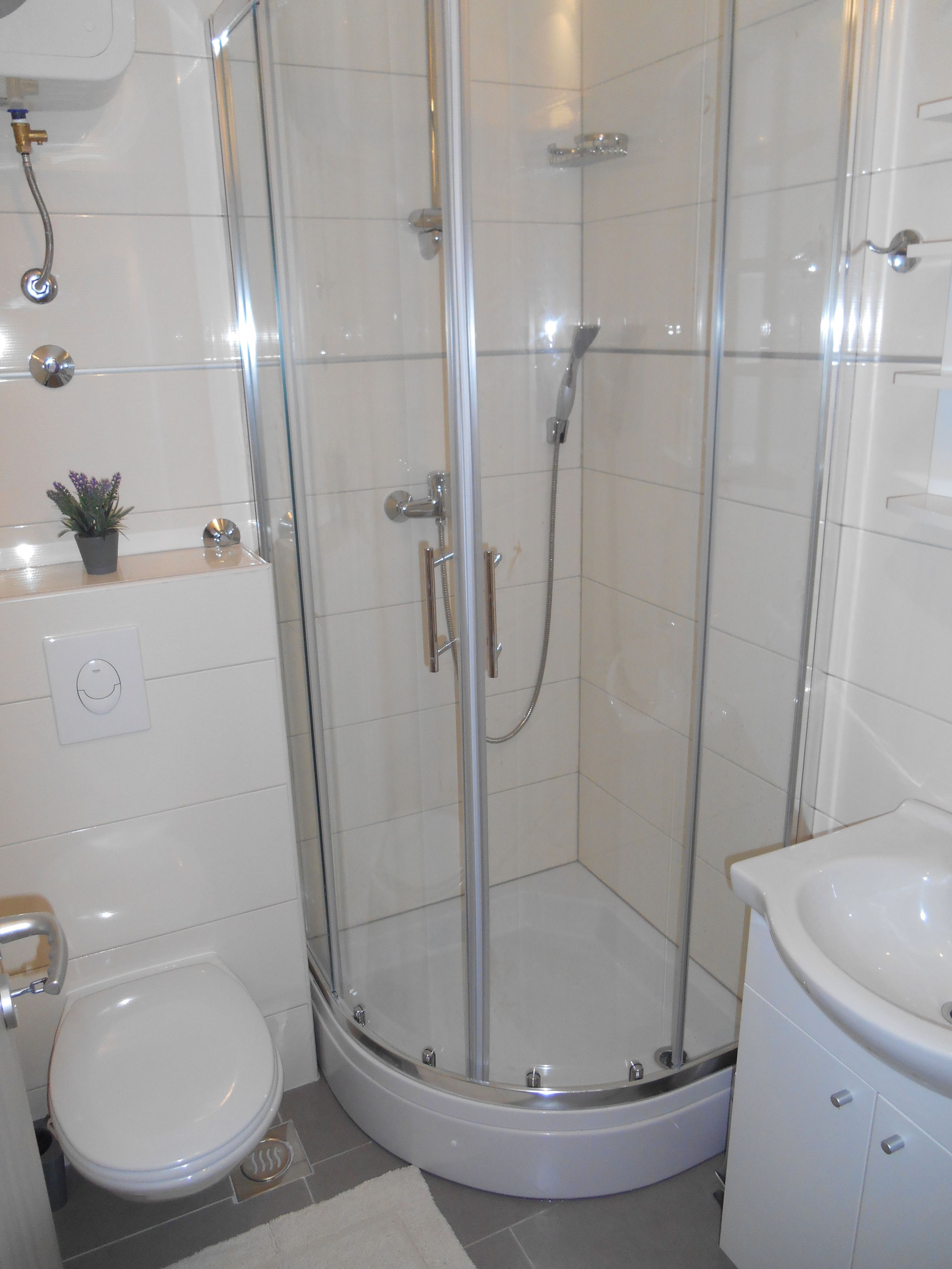 Une salle de bain moderne dotée d’une douche à parois de verre, de toilettes et d’un lavabo.