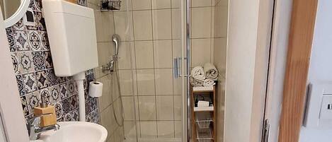 A compact bathroom with a toilet, sink, and shower.