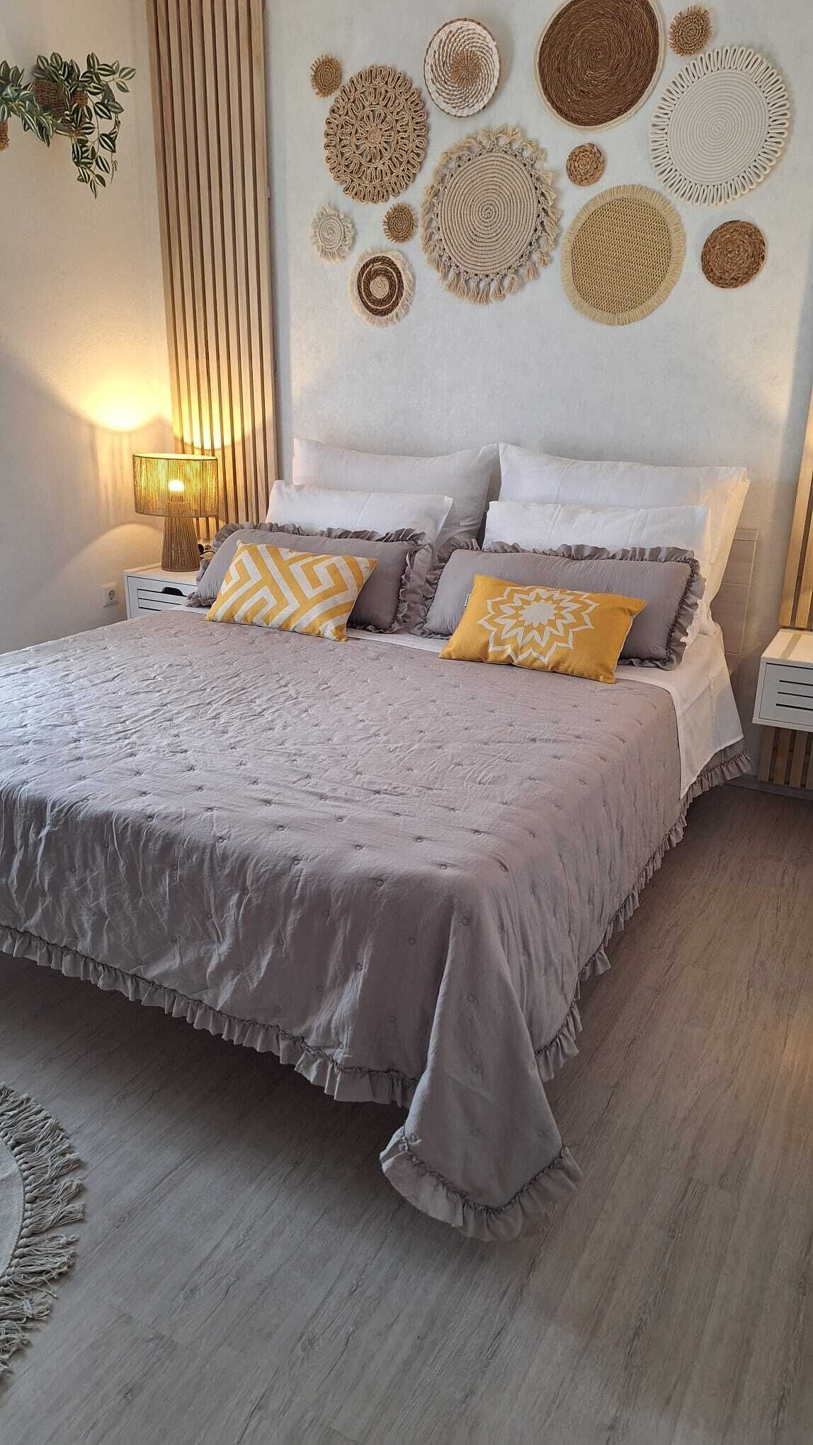 Un dormitorio ordenado con una cama grande, una mesita de noche y un adorno en la pared.