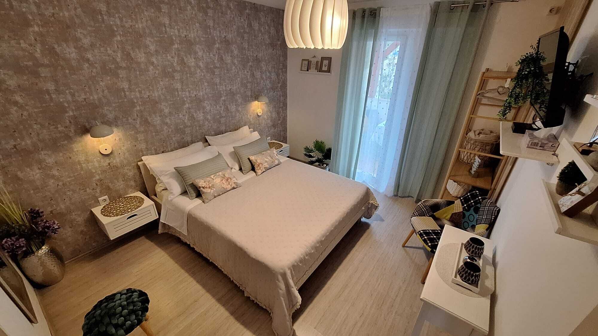 A modern bedroom with a large bed, bedside tables, a desk, and a hanging light fixture.
