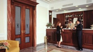 A hotel lobby with a reception desk, a yellow armchair, and a marble floor. - Hotel Civita (Atripalda)