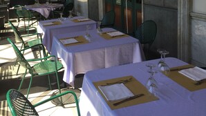 A restaurant with outdoor seating, tables set with white tablecloths and green chairs, and a view of the street. - Hotel Civita (Atripalda)