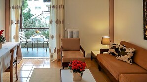 Un salon comprenant un canapé, une table ornée d’un vase de fleurs, un fauteuil, une lampe et une vue sur l’extérieur.