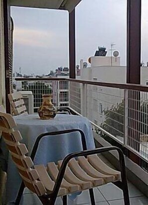 A balcony with a table, two chairs, and a vase.
