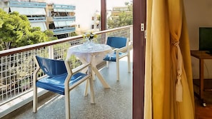 A balcony with a table and chairs, a railing, and a view of buildings and trees.