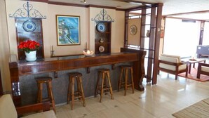 Un coin bar avec des tabourets, un tableau et des assiettes décoratives exposées sur des étagères.
