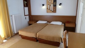 Un lit double avec une tête de lit en bois, deux tables de chevet, une petite table et un radiateur.