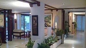 Un vaste espace de vie au design moderne, comprenant une grande fenêtre, une cheminée et un coin salon avec un canapé et des fauteuils.