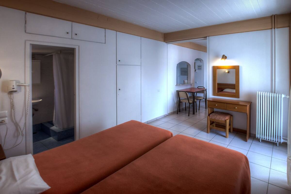 Une chambre avec deux lits, un bureau, une chaise, un miroir et un radiateur.