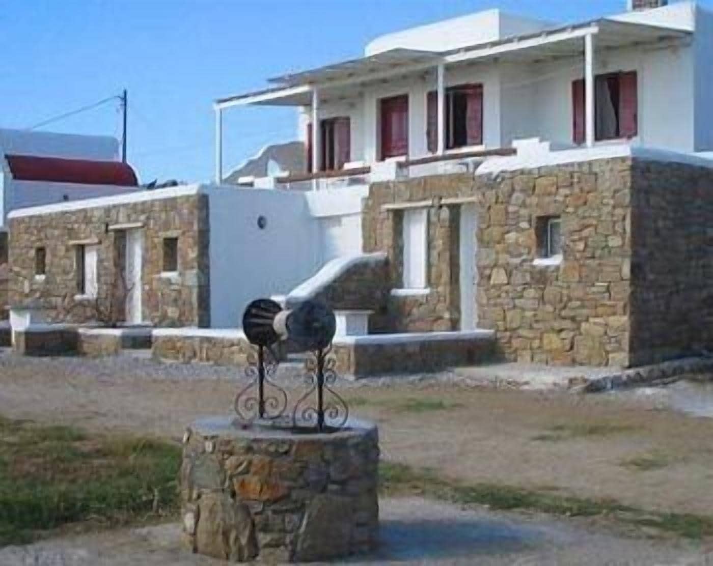 A stone building with a balcony and a metal sculpture in front.