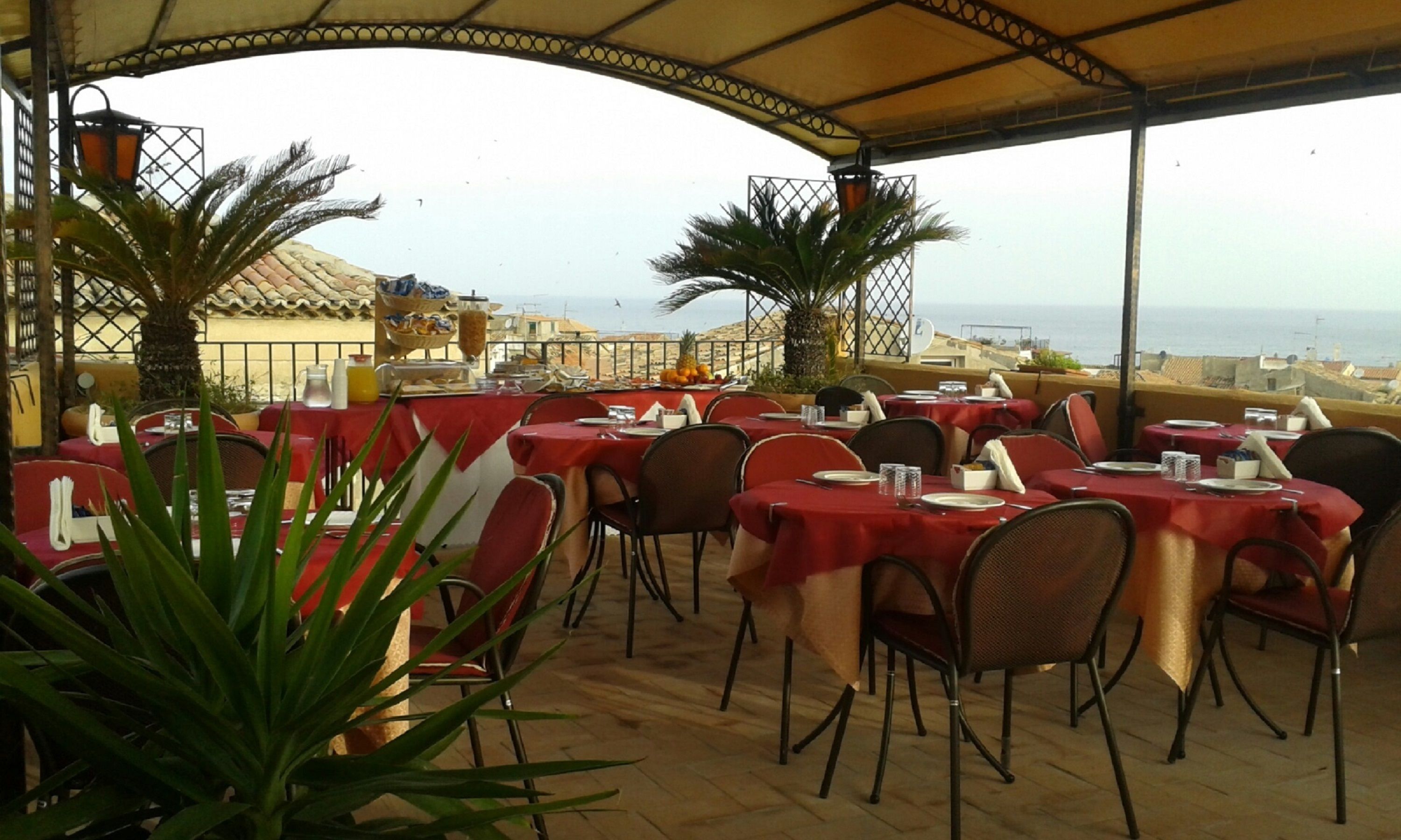 An outdoor dining area with tables set for guests, overlooking a coastal view.