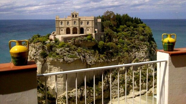 A coastal building with a balcony, overlooking the sea.