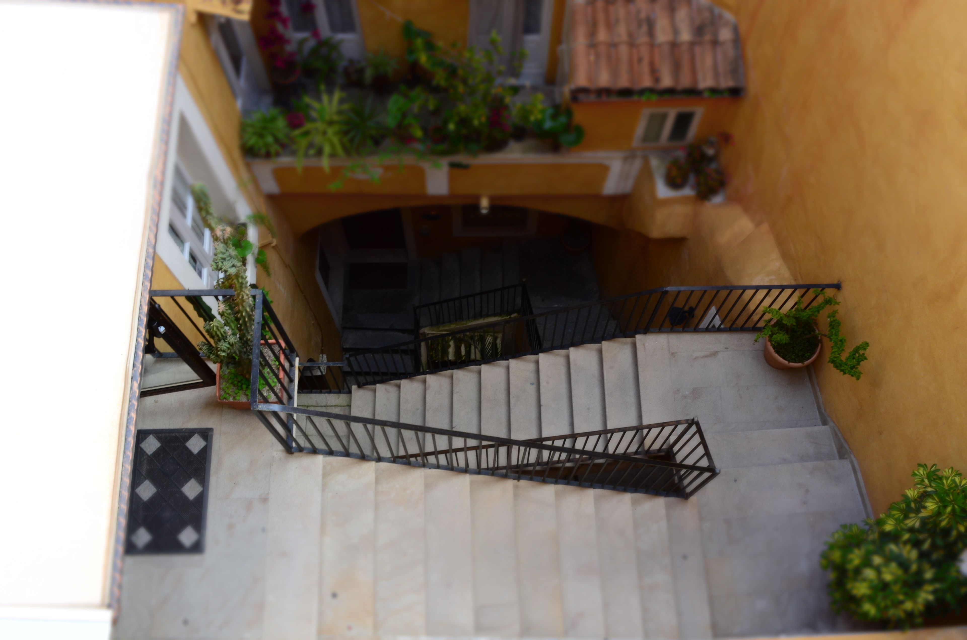 A narrow staircase with metal railings, leading to a landing with a door.