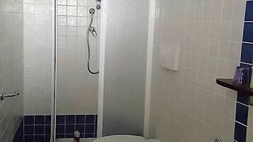 Un bagno con doccia, due servizi igienici e un lavandino.