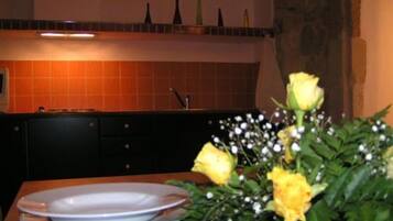 A dining table with plates and a vase of yellow flowers.